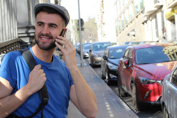 Nahaufnahme Porträt eines gutaussehenden jungen Mannes in lässiger Kleidung, der auf einer europäischen Straße telefoniert - Foto, Bild