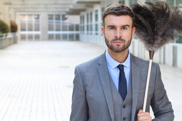 close-up portrait of handsome young businessman with feather duster on street - 写真・画像