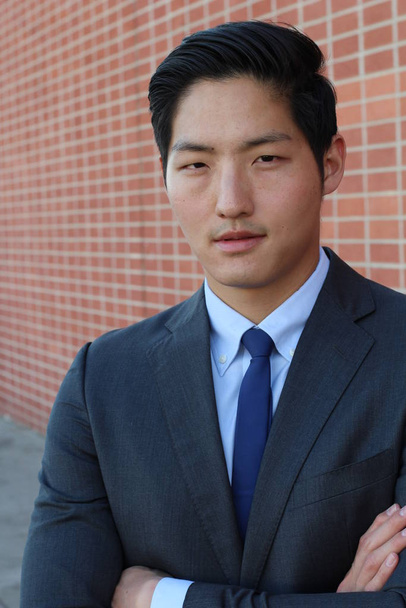 közeli kép jóképű fiatal ázsiai üzletemberről a téglafal előtt - Fotó, kép