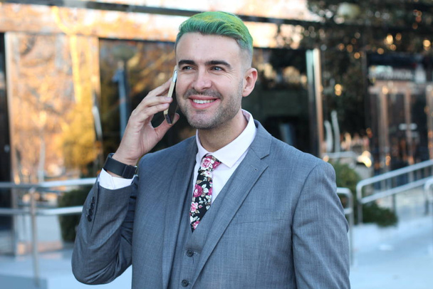 Elegant handsome man with green hair using phone in office space - Photo, Image
