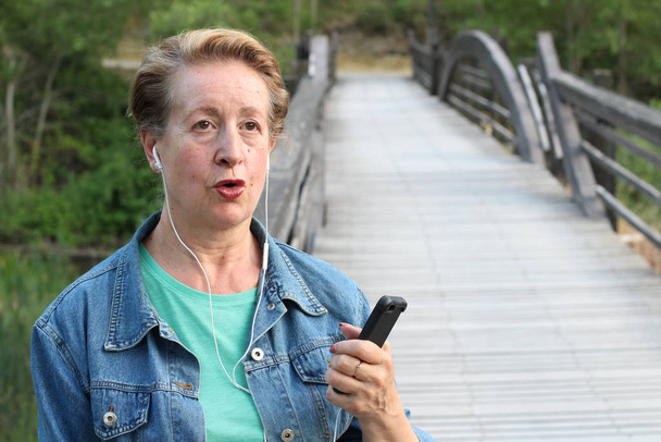 Mature woman using a smart phone outdoors - Photo, Image