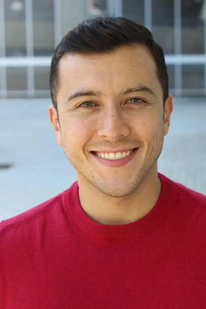 közeli kép egy jóképű fiatalemberről piros pulóverben az utcán - Fotó, kép
