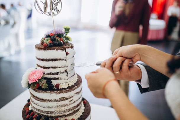 A bride and a groom is cutting their beautiful wedding cake. nicel light. wedding concept - Valokuva, kuva