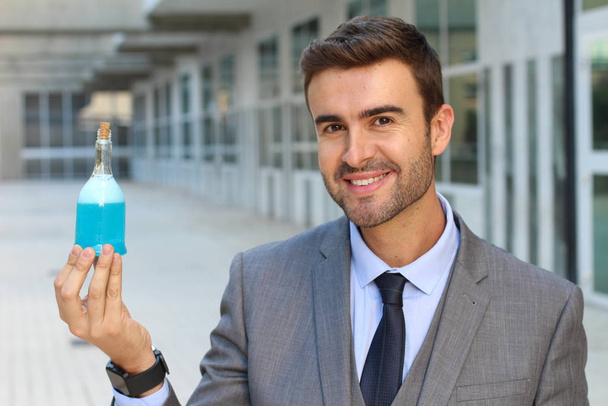 close-up retrato de belo jovem empresário segurando garrafa de poção azul na rua
 - Foto, Imagem