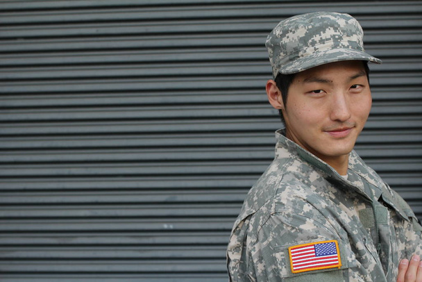 közeli kép egy jóképű fiatal ázsiai katonáról a fal előtt. - Fotó, kép