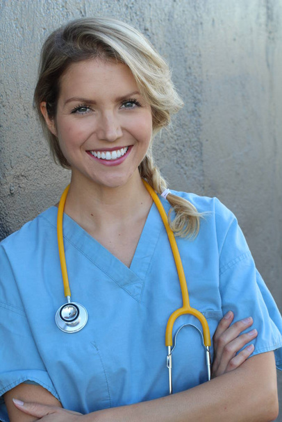 Medical professionals: Woman nurse smiling while working at hospital. Young beautiful blond Caucasian female health care worker - Photo, Image