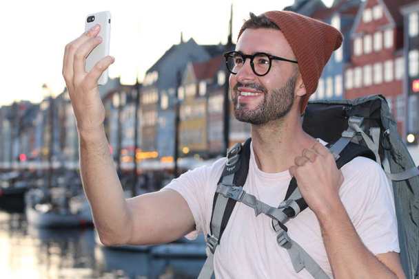 Backpacker sorridente durante la realizzazione di selfie in epico Nyhavn, Copenaghen, Danimarca
. - Foto, immagini