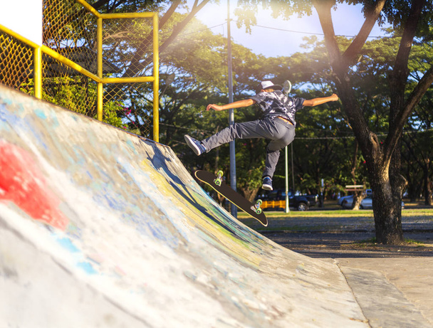 Молодий хлопчик стрибає на рампі зі скейтбордом на відкритому повітрі
. - Фото, зображення