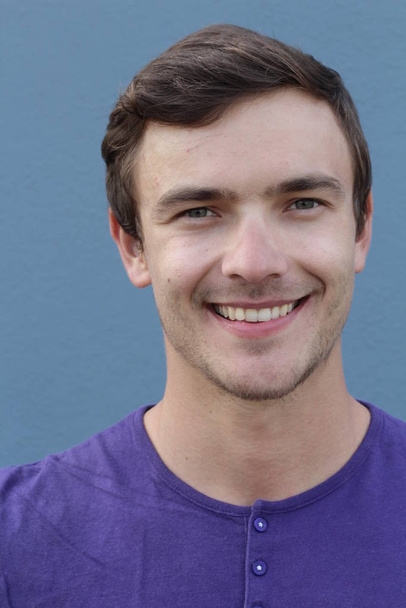 közeli kép egy jóképű fiatalemberről lila ingben a kék fal előtt - Fotó, kép