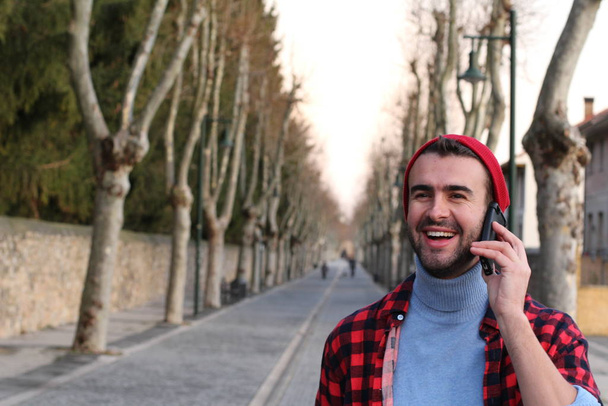 close-up portret van knappe jonge man praten via de telefoon op straat - Foto, afbeelding