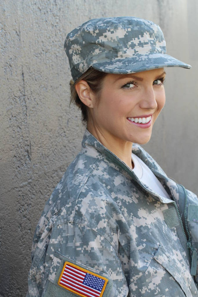 Gorgeous young woman in a Military costume on gray background - 写真・画像