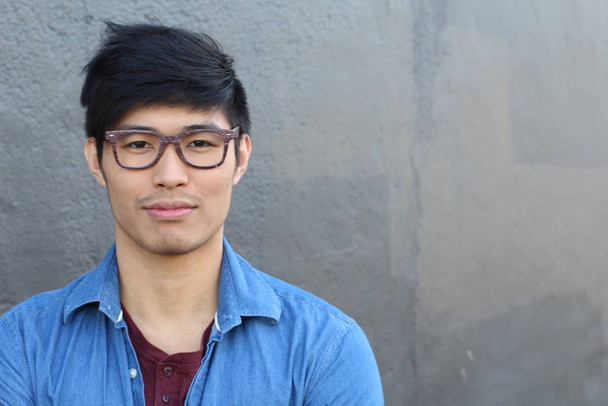 zblízka portrét pohledného mladého asijského muže před šedou stěnou - Fotografie, Obrázek