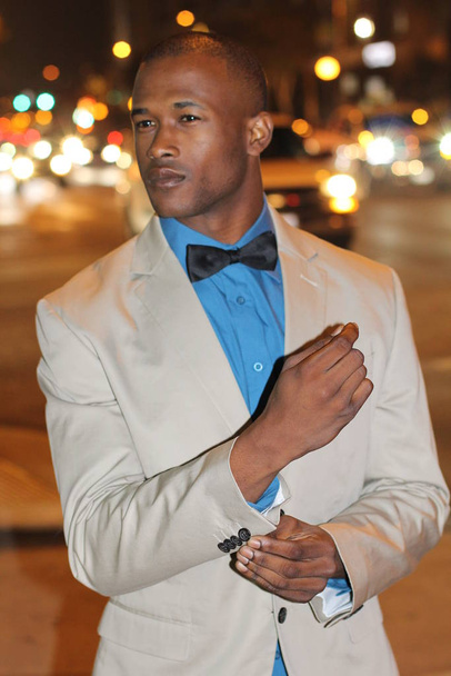 ベージュスーツのハンサムな若いビジネスマンのクローズアップ肖像夜に路上で蝶ネクタイ - 写真・画像