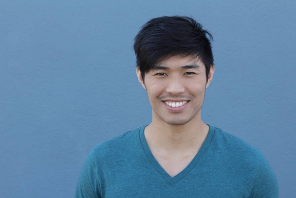 közeli kép egy jóképű, fiatal ázsiai férfiról a kék fal előtt - Fotó, kép