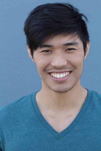 close-up portrait of handsome young asian man in front of blue wall - Photo, Image