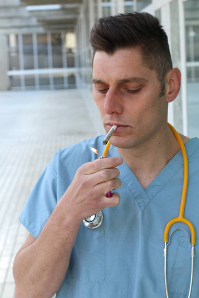 primer plano retrato de guapo joven médico con estetoscopio fumar cigarrillo en la calle
 - Foto, imagen