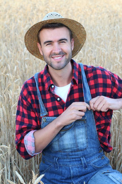 primer plano retrato de joven guapo en ropa de los agricultores y sombrero de paja en el campo de trigo en la naturaleza
 - Foto, imagen