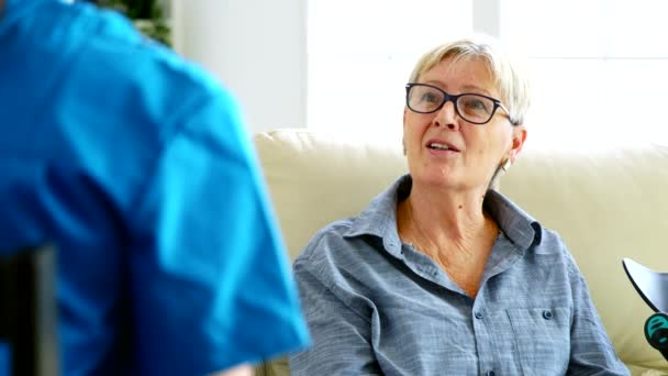 Vanhempi vanha nainen istuu sohvalla hoitokodissa puhumassa lääkärin kanssa - Materiaali, video