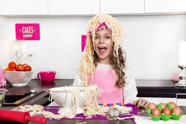 Verbaasd grappig meisje met pasta op het hoofd - Foto, afbeelding