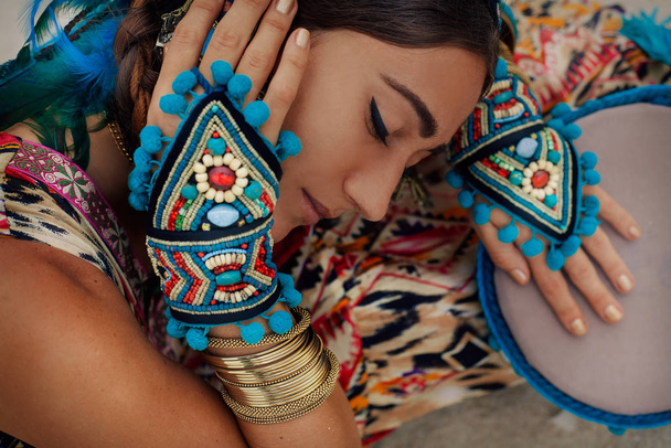 attractive young woman in ethnic jewelry outdoors - Фото, зображення