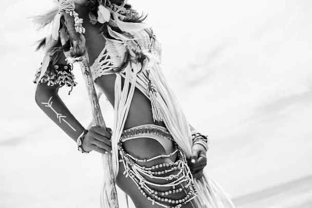 abgeschnittenes Bild einer wilden Boho-Frau in indianischem Stil und weißer Kleidung, die in der Natur posiert - Foto, Bild