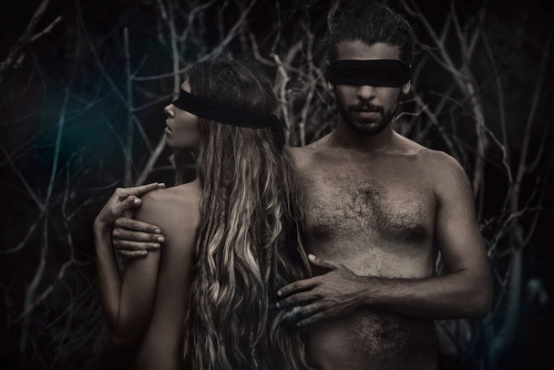 attractive young man and woman with eyes closed conceptual posing in forest - Фото, изображение