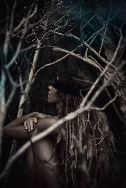 Young beautiful blindfolded woman in dark spooky forest - Fotoğraf, Görsel