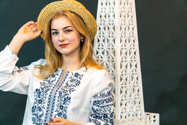 fiatal nő visel fonott kalap és hímzett ing pózol stúdióban - Fotó, kép