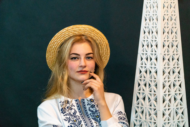 młoda kobieta w wiklinowym kapeluszu i haftowanej koszuli pozowanie w studio - Zdjęcie, obraz