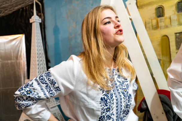 szőke nő hímzett ing beszél, miközben áll a stúdióban - Fotó, kép