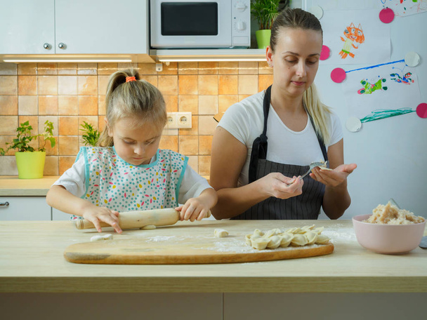 Fiatal anya kislányával főz a konyhában - Fotó, kép
