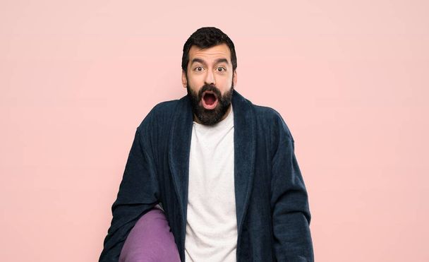 Man with beard in pajamas with surprise facial expression over isolated pink background - Fotoğraf, Görsel