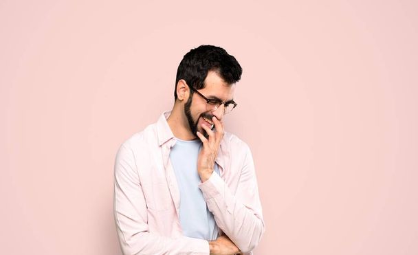 Jóképű férfi szakállal sokat mosolyog elszigetelt rózsaszín háttér - Fotó, kép