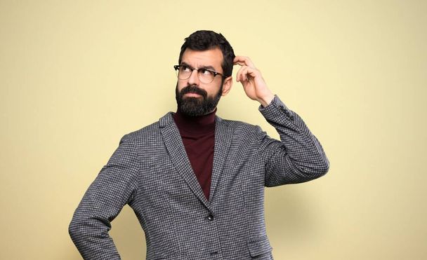 Handsome man with glasses having doubts while scratching head - Foto, afbeelding