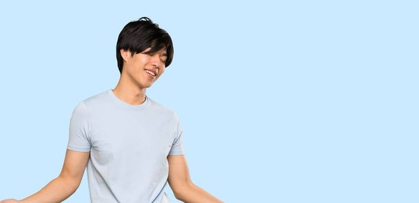 Aasialainen mies sininen paita hymyilee yli eristetty sininen tausta
 - Valokuva, kuva