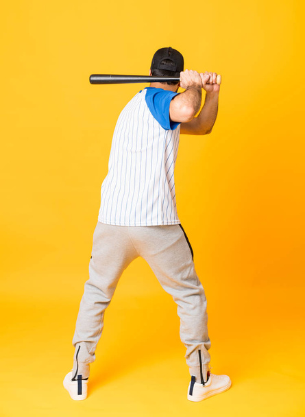 Full-length shot of man over isolated yellow background playing baseball - Foto, imagen