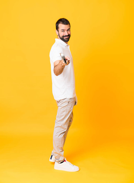 Full-length shot of a man playing golf over isolated yellow background - Φωτογραφία, εικόνα