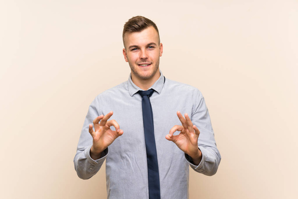 Joven hombre de negocios rubia sobre fondo aislado mostrando un signo de ok con los dedos
 - Foto, Imagen