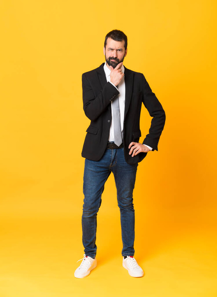 Full-length shot of business man over isolated yellow background thinking - Fotó, kép