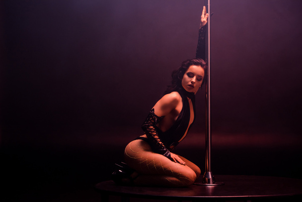 beautiful stripper dancing near pylon on black with copy space - Фото, изображение