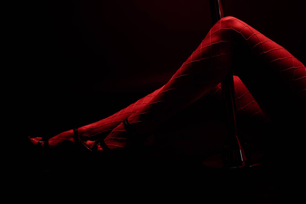 oříznutý pohled na červené osvětlení na sexy striptérce izolované na černé s červeným osvětlením  - Fotografie, Obrázek