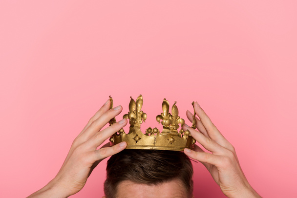 ピンクの背景に王冠を被った男のクロップドビュー   - 写真・画像