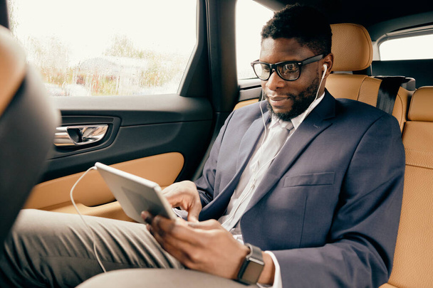 Man scrolling through the tablet screen during car ride. - Фото, зображення