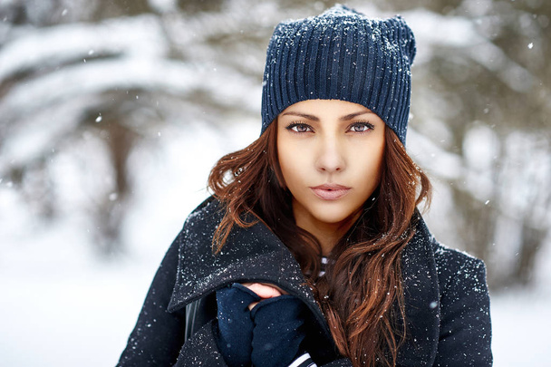 Winter fashion portrait of a beautiful woman in snowy park in ha - Photo, Image