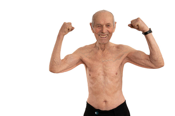 Retrato de meia distância do velho sem camisa feliz, sênior mostrando seu bíceps e olhando para a câmera isolada sobre o fundo branco
 - Foto, Imagem