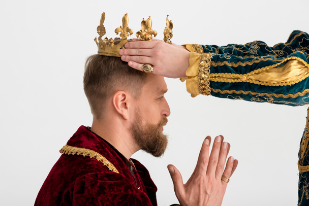 cropped view of man putting crown on king with praying hands on grey background  - Photo, Image