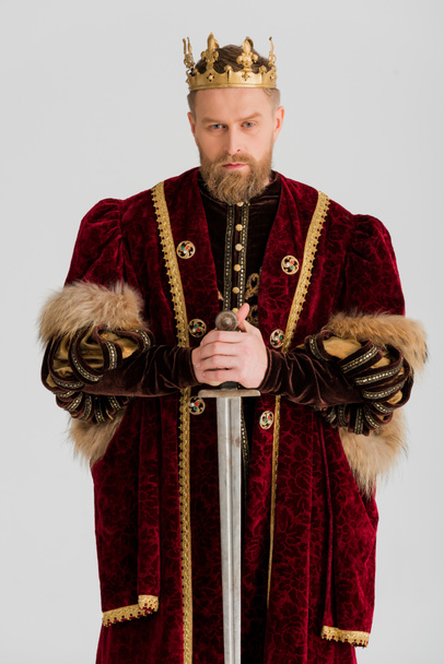 vážný král s korunou drží meč izolovaný na šedi - Fotografie, Obrázek