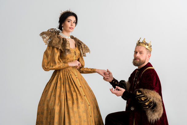 король с короной на коленях и держась за руки с королевой, изолированной на сером
 - Фото, изображение