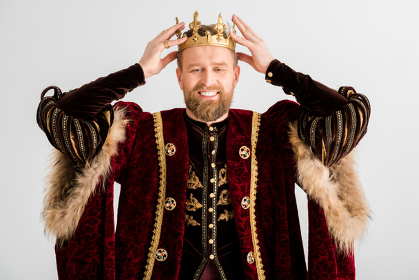 glimlachende koning draagt kroon op hoofd geïsoleerd op grijs - Foto, afbeelding