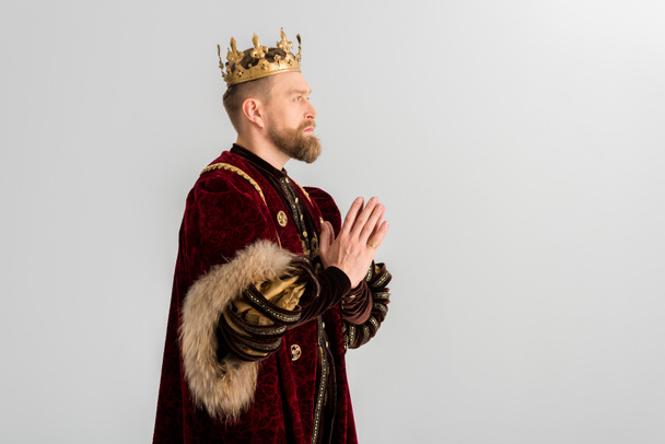 side view of king with crown praying isolated on grey - Photo, Image